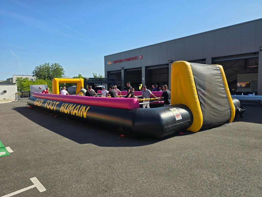 Vue latérale du baby foot humain avec des joueurs a l'interieur.