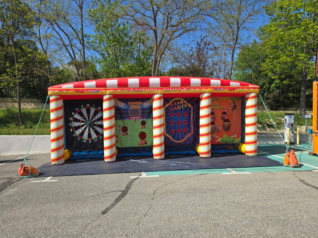 Stand gonflable de kermesse avec 4 jeux d’adresse alignés : cible, lancer, fléchettes, frisbee