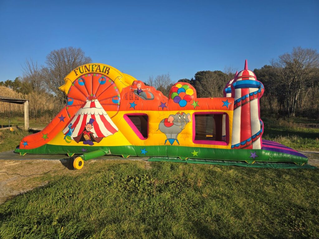 Vue de côté du parcours gonflable Fun Fair aux couleurs de fête foraine.