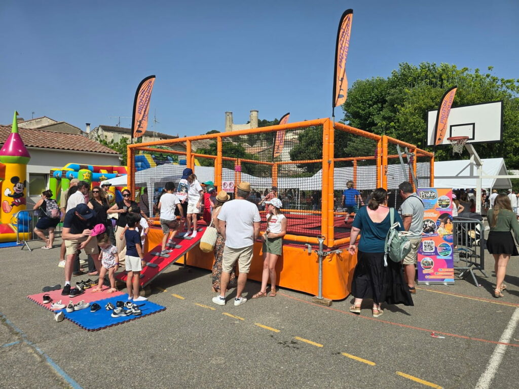 Batterie de trampoline 6 pistes vue de biais avec des enfants qui jouent à l'intérieur installée pour une kermesse à Châteaurenard