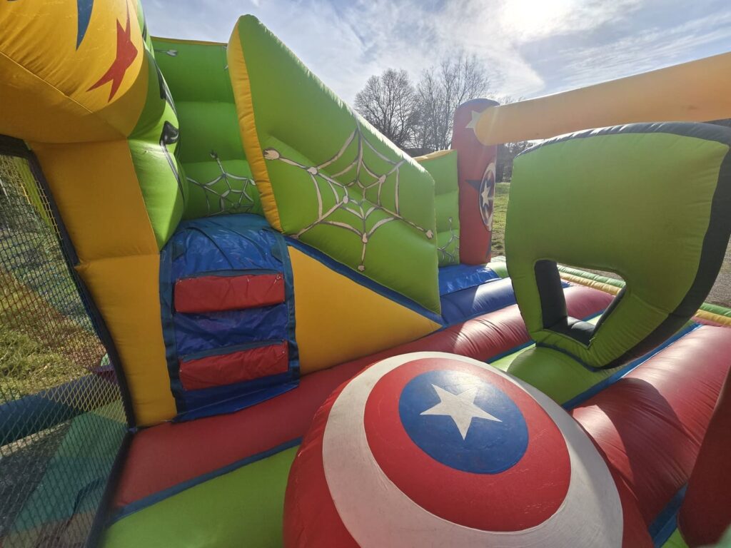 Intérieur du château gonflable combo Avengers avec obstacles et décorations de personnages.