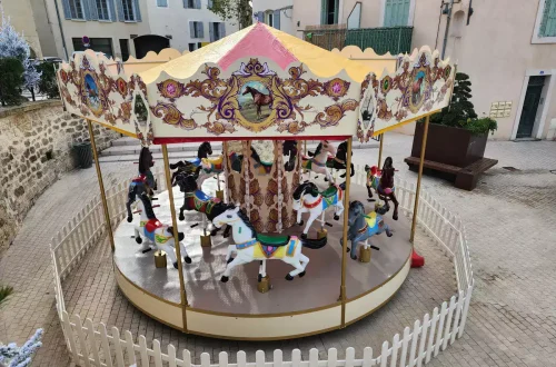 Vue en hauteur d’un carrousel rétro installé avec clôture blanche.